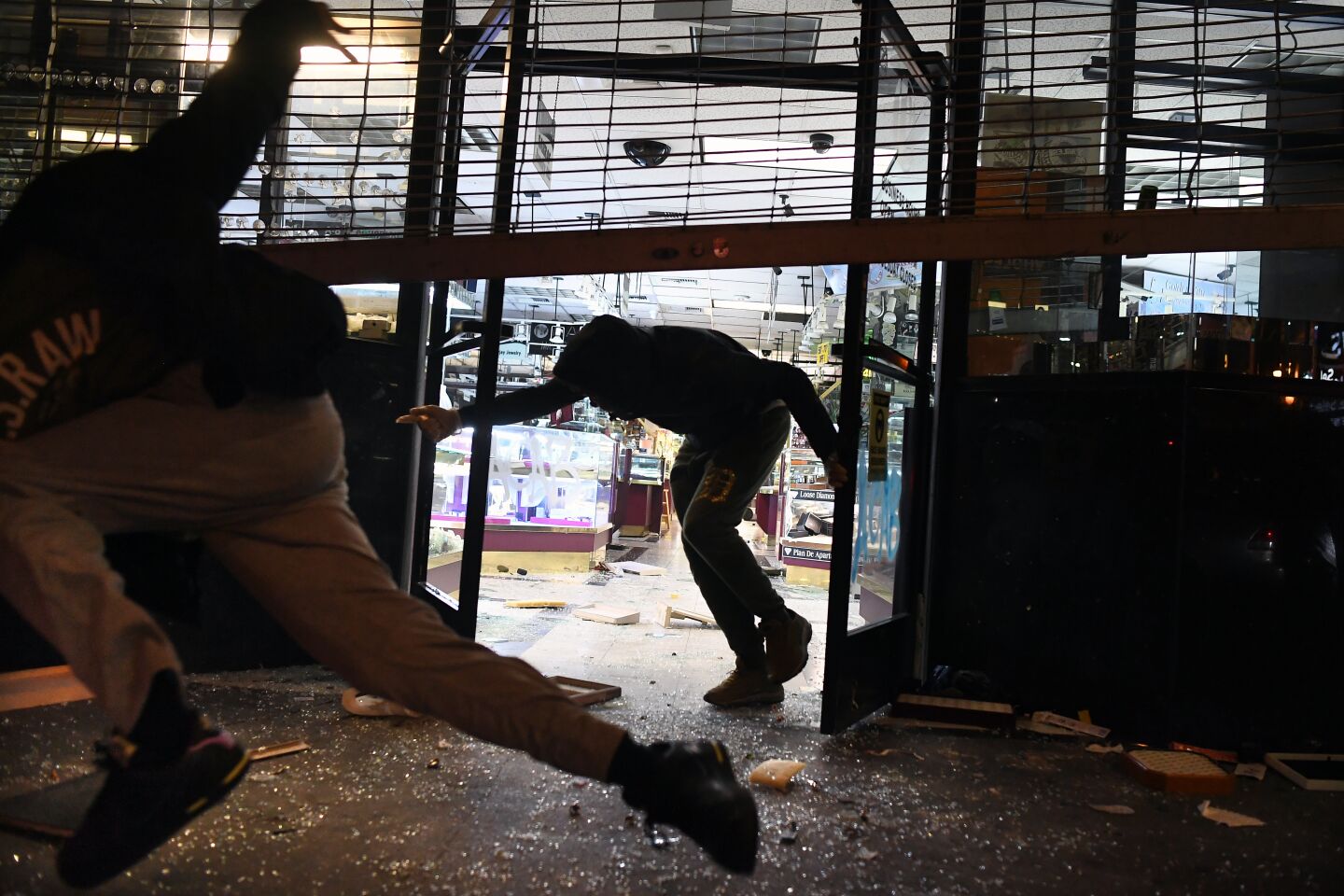People run from a burglarized jewelry store as LAPD officers approach in downtown Los Angeles