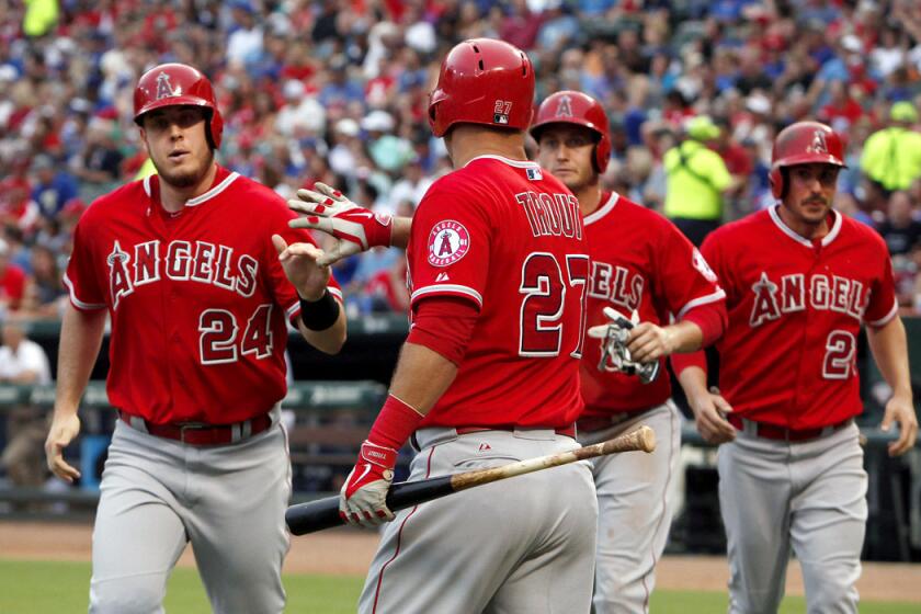 Los Angeles Angels designated hitter C.J. Cron (24) is greeted at home by Mike Trout (27) after he, David Freese, middle back, and Matt Joyce scored against the Texas Rangers during an Angels 8-2 rout.