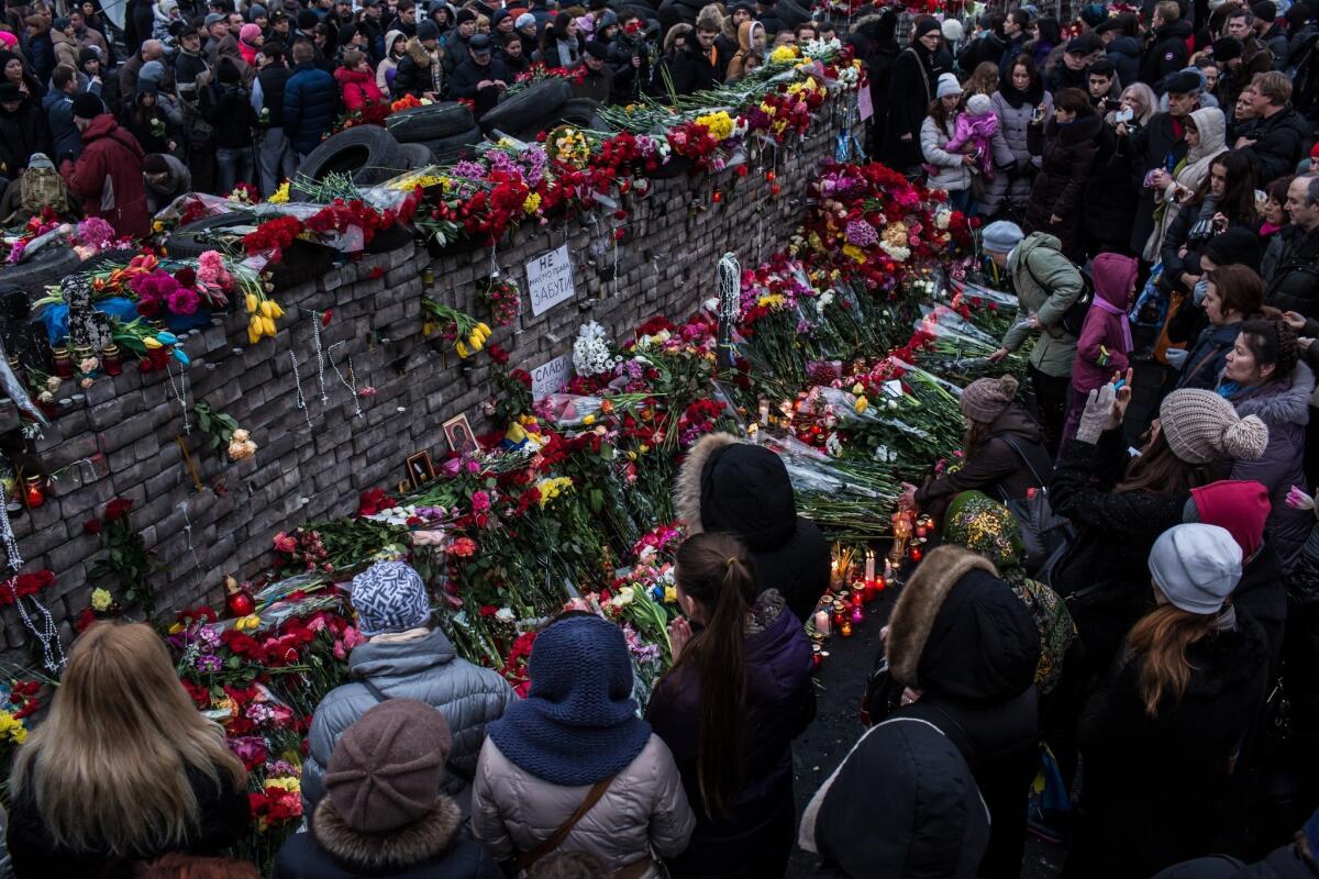 People lay flowers and pay their respects at a memorial for anti-government protesters killed in clashes with police in Kiev's Independence Square on Sunday.