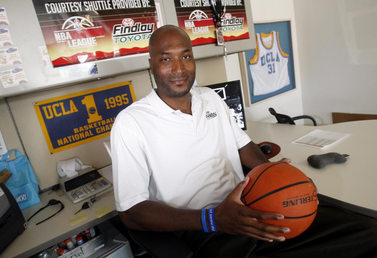 Former UCLA basketball player Ed O'Bannon Jr. holds a basketball while sitting in an office decorated with Bruins memorabilia