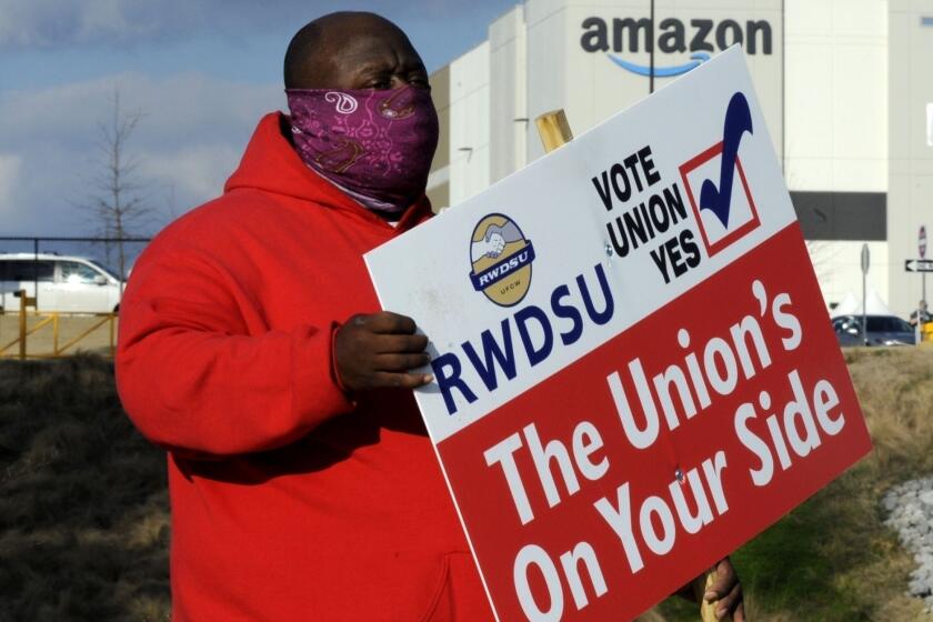 FILE - In this Tuesday, Feb. 9, 2021, file photo, Michael Foster of the Retail, Wholesale and Department Store Union holds a sign outside an Amazon facility where labor is trying to organize workers in Bessemer, Ala. Nearly 6,000 Amazon warehouse workers in Bessemer are deciding whether they want to form a union, the biggest labor push in the online shopping giant's history. Mail-in voting started in early February. Ballots must be received by the end of Monday March 29, 2021. The National Labor Relations Board starts counting votes the next day. (AP Photo/Jay Reeves, File)