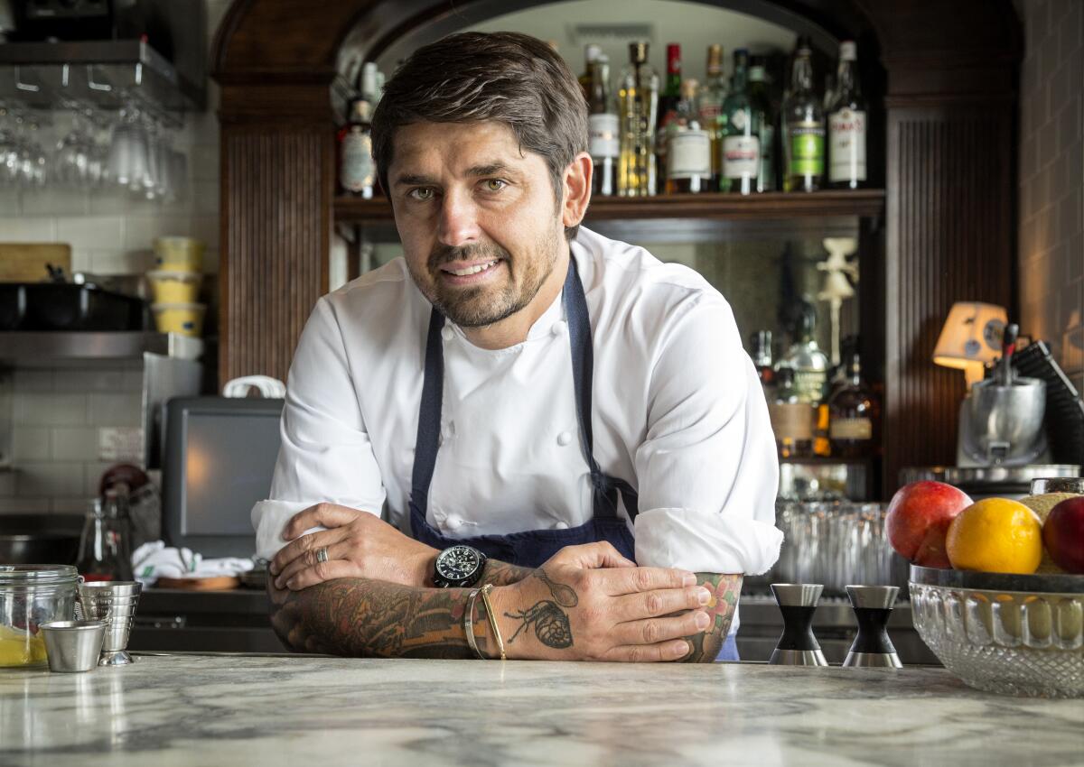 Chef Ludo Lefebvre leans against the marble-topped bar of Petit Trois in Hollywood, arms folded and looking at the camera.