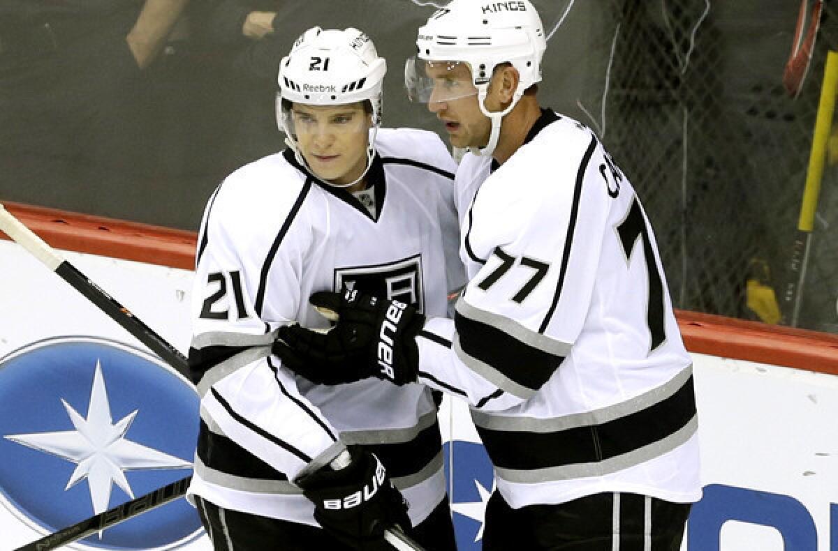 Kings forwards Matt Frattin (21) and Jeff Carter (77) celebrate after a goal by Carter against the Wild during a season-opening, 3-2 victory in Minnesota.