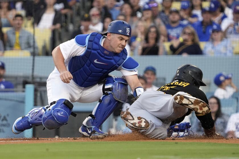 Pittsburgh Pirates' Carlos Santana, right, is tagged out at home by Los Angeles Dodgers catcher Will Smith as he tries to score on a fielder's choice hit by Nick Gonzales during the second inning of a baseball game Monday, July 3, 2023, in Los Angeles. (AP Photo/Mark J. Terrill)