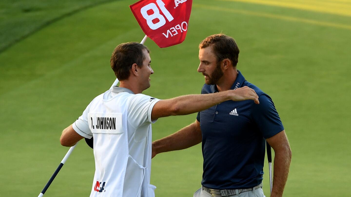 Dustin Johnson, right, gets a congratulatory hug from his caddie and younger brother Austin after making a birdie on the 18th hole Sunday at the U.S. Open.
