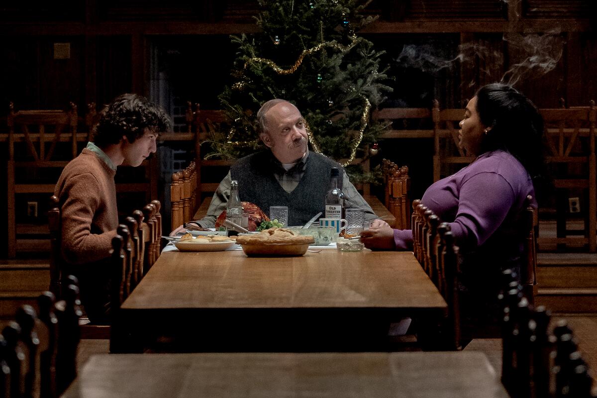 A young man, an older man and a woman share a meal together at a dining table in "The Holdovers."