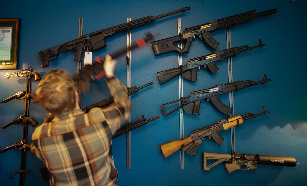 A man places a rifle on a wall rack