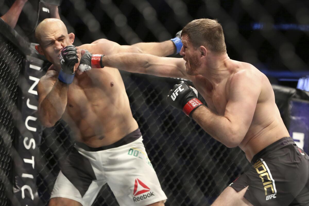 Stipe Miocic hits Junior Dos Santos with a right hand during their heavyweight title fight at UFC 211 in Dallas on May 13.
