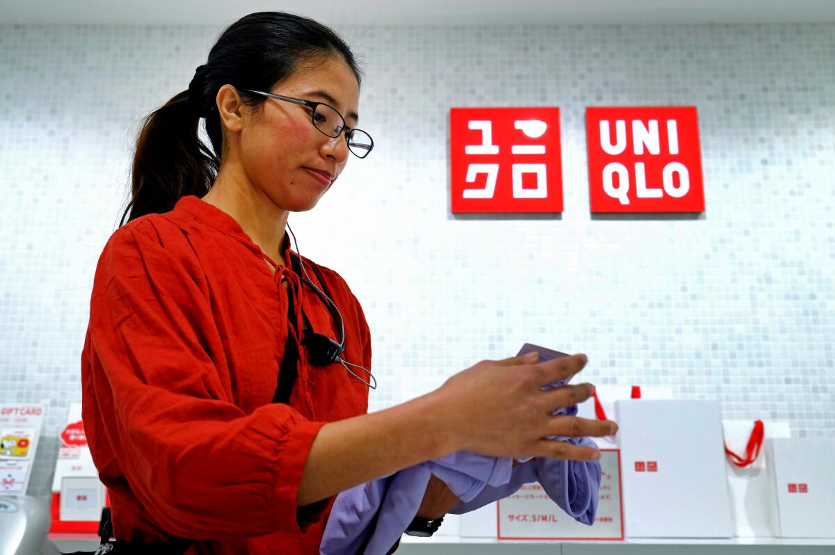 Cing, a refugee from Myanmar, works at a Uniqlo clothing shop in Tokyo in 2018. An aging Japan is increasing automation as it struggles to fill jobs.