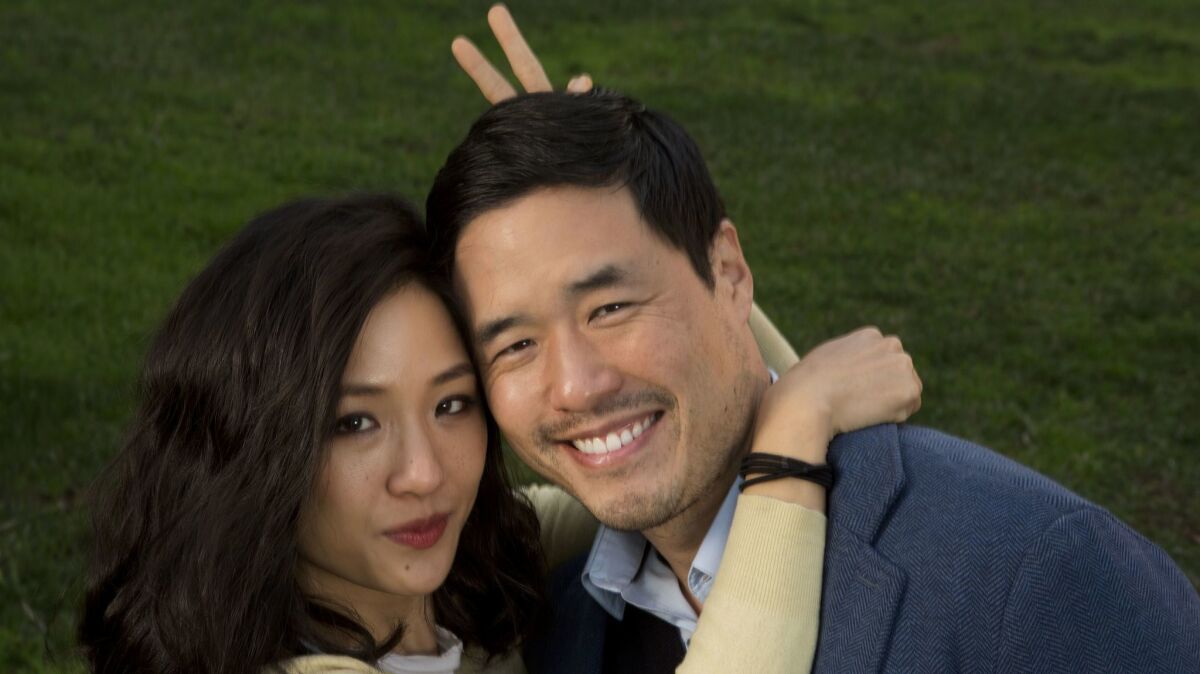 Constance Wu and Randall Park in "Fresh Off the Boat." She has her arms around him and is doing bunny ears behind his head.