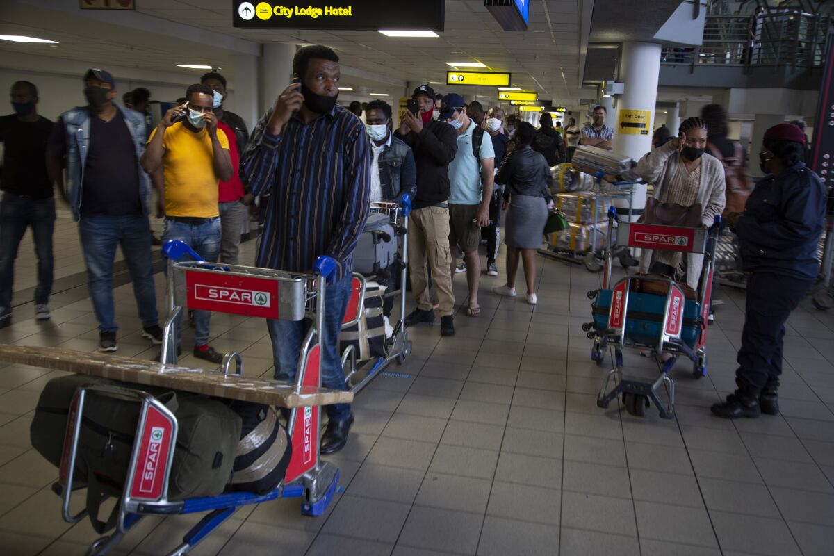 FILE — In this Oct.1, 2020 file photo passengers queue to access the O.R. Tambo Airport in Johannesburg, South African travel agencies are reporting a surge in reservations for travel to and from Britain ahead of the country being removed from the U.K.'s COVID-19 red list next week. (AP Photo/Denis Farrell/File)