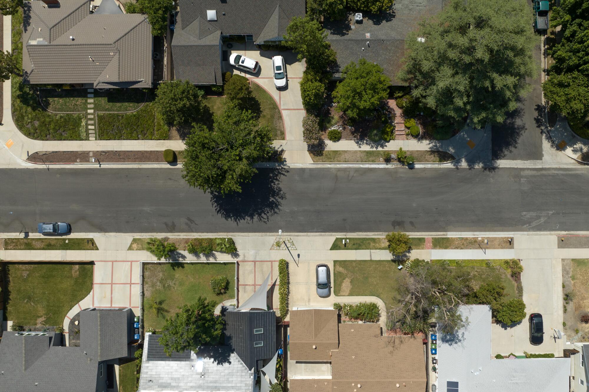 An aerial view of a residential street with green lawns