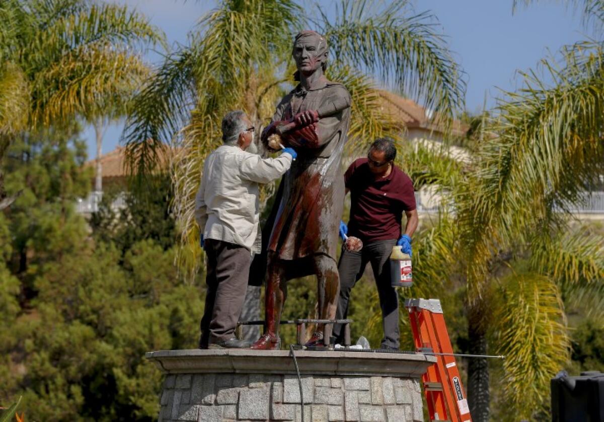 Workers clean red paint off the Christopher Columbus statue at Discovery Park in Chula Vista last year