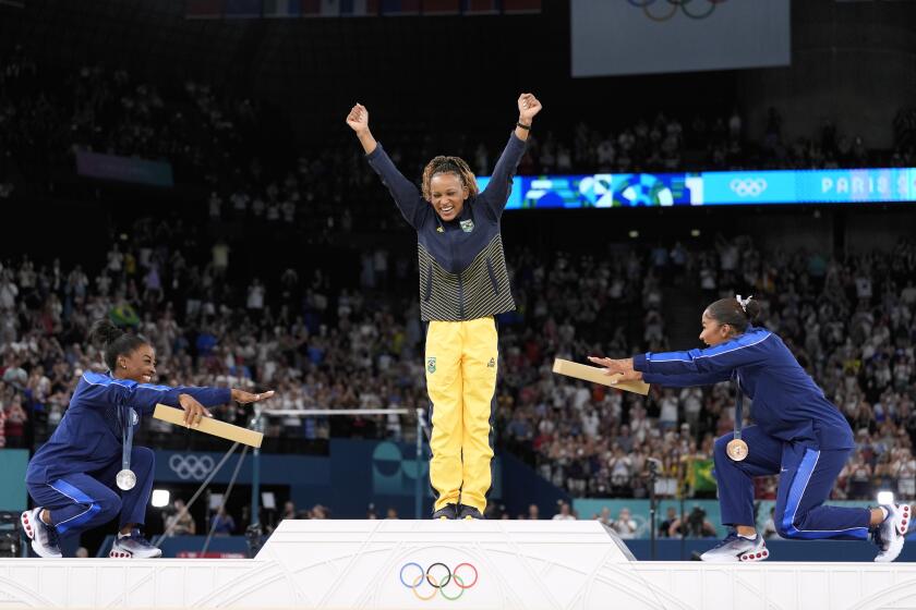 La medalllista de plata Simone Biles (izquierda) y la medallista de bronce Jordan Chiles se inclinan ante la campeona brasileña Rebeca Andrade tras ganar la medalla de oro en el ejercicio de piso de los Juegos Olímpicos de París, el lunes 5 de agosto de 2024. (AP Foto/Abbie Parr)