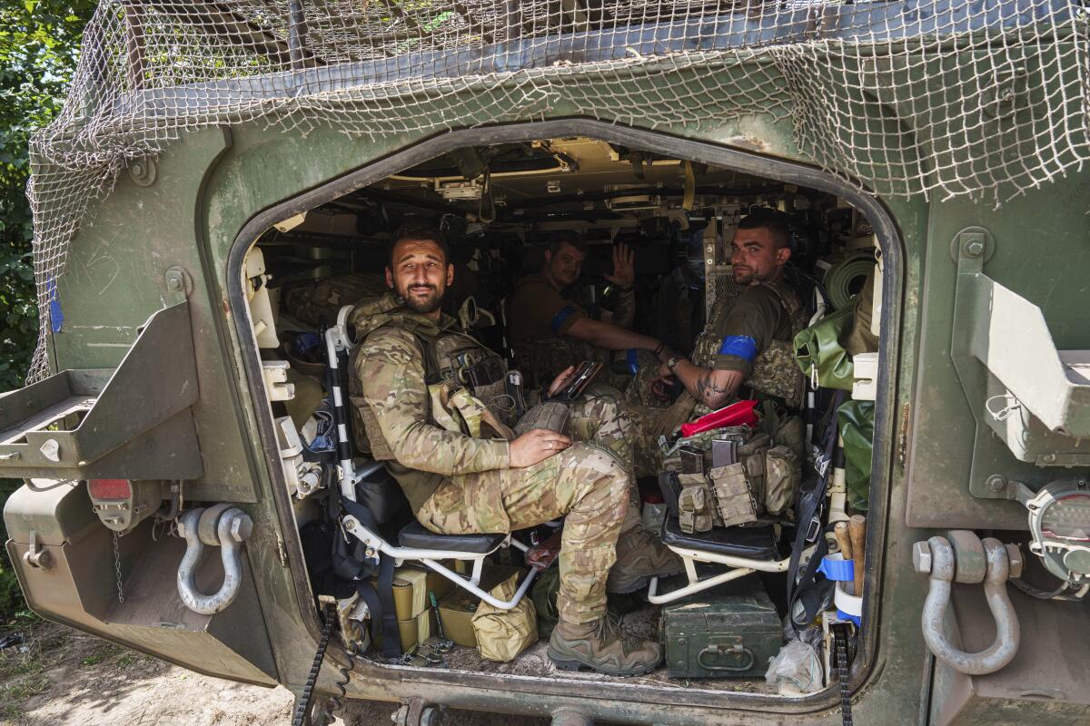 Ukrainian servicemen in camoflauge uniforms sit in an armored personnel carrier.