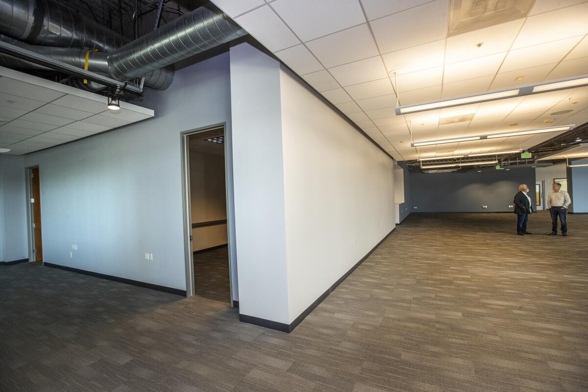 This photo shows two men standing in empty office space
