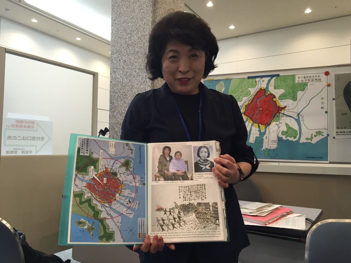 Michiko Yamaoka, 65, is a volunteer at the Hiroshima peace memorial museum. She is holding a scrapbook that shows a photo of her with her mother, and her mother's sister, at right.