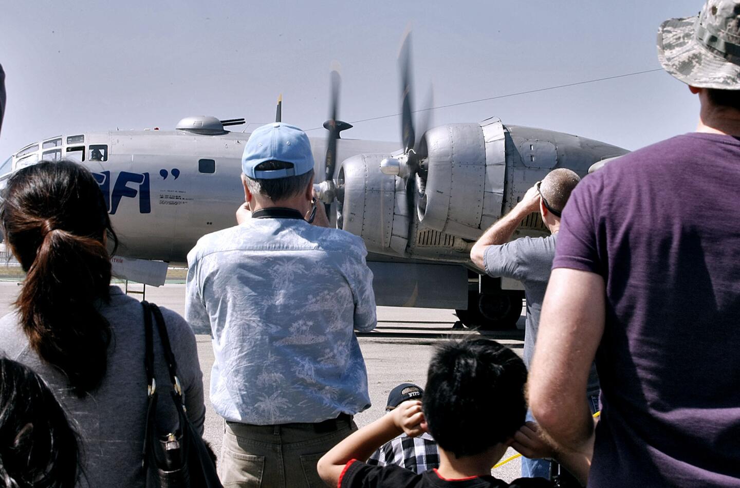 Aviation enthusiasts watch a B-29 Superfortress named "Fifi" as it turns its engines while parked at the Burbank Airport on Saturday, March 23, 2013. After two engine tests, it was determined that a mechanical malfunction would keep the World War II-era bomber grounded for the day.