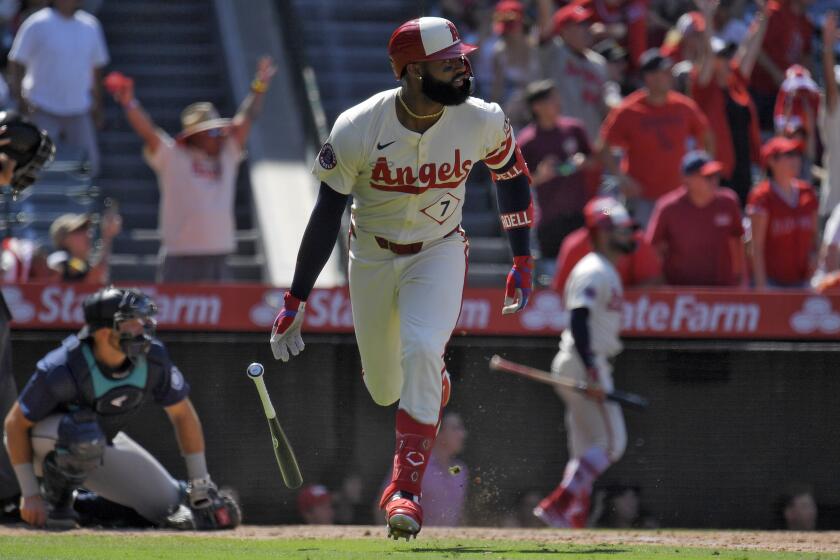 Los Angeles Angels' Jo Adell, right, heads to first for a three-run home run as Seattle Mariners.