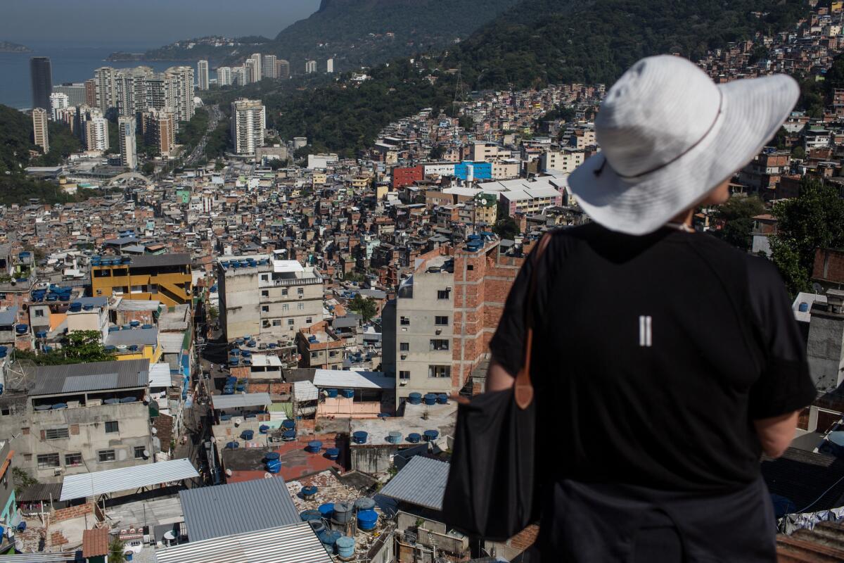 RIO DE JANEIRO, BRAZIL - AUGUST 17: A tourist takes in the view from a rooftop during a tour of Rochina 'favela' community on August 17, 2016 in Rio de Janeiro, Brazil. With the Rio 2016 Olympic games currently underway, for many 'favela ' communities tourism has become a source of income in the lead up and during the games. The governments 'pacification' plan has seen some favela communities become safe enough for tour groups to run daily walking and jeep tours. Around 1.4 million residents, or approximately 22 percent of Rio's population, reside in favelas which often lack proper sanitation, health care, education and security due to gang and police violence. (Photo by Chris McGrath/Getty Images) ** OUTS - ELSENT, FPG, CM - OUTS * NM, PH, VA if sourced by CT, LA or MoD **
