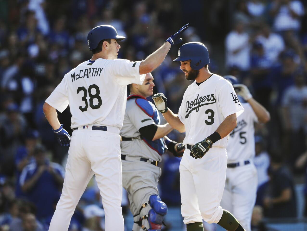 Dodgers center fielder Chris Taylor (3) gets a slap on the helmet from starting pitcher Brandon McCarthy (38) after hitting a home run against the Cubs during the fifth inning.