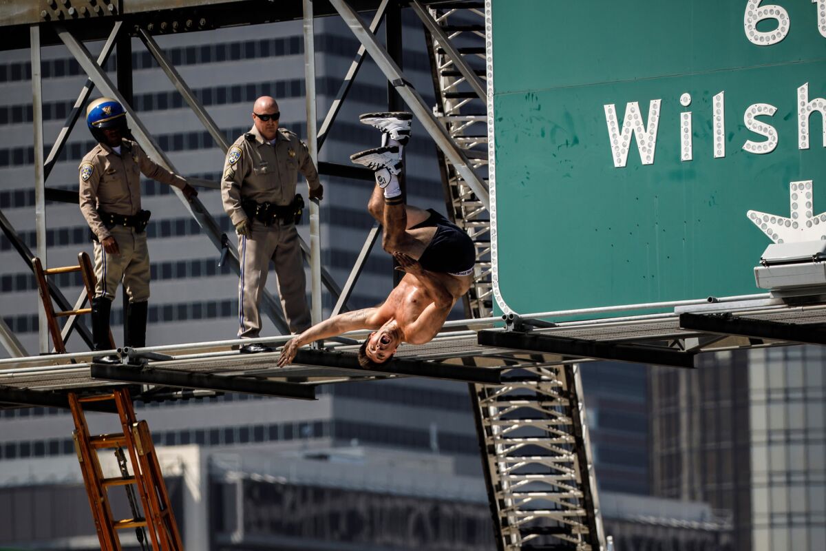 California Highway Patrol officers watch as a man who had scaled a freeway sign and shut down the southbound 110 Freeway does a backflip onto massive inflatable cushions set up below in downtown Los Angeles.