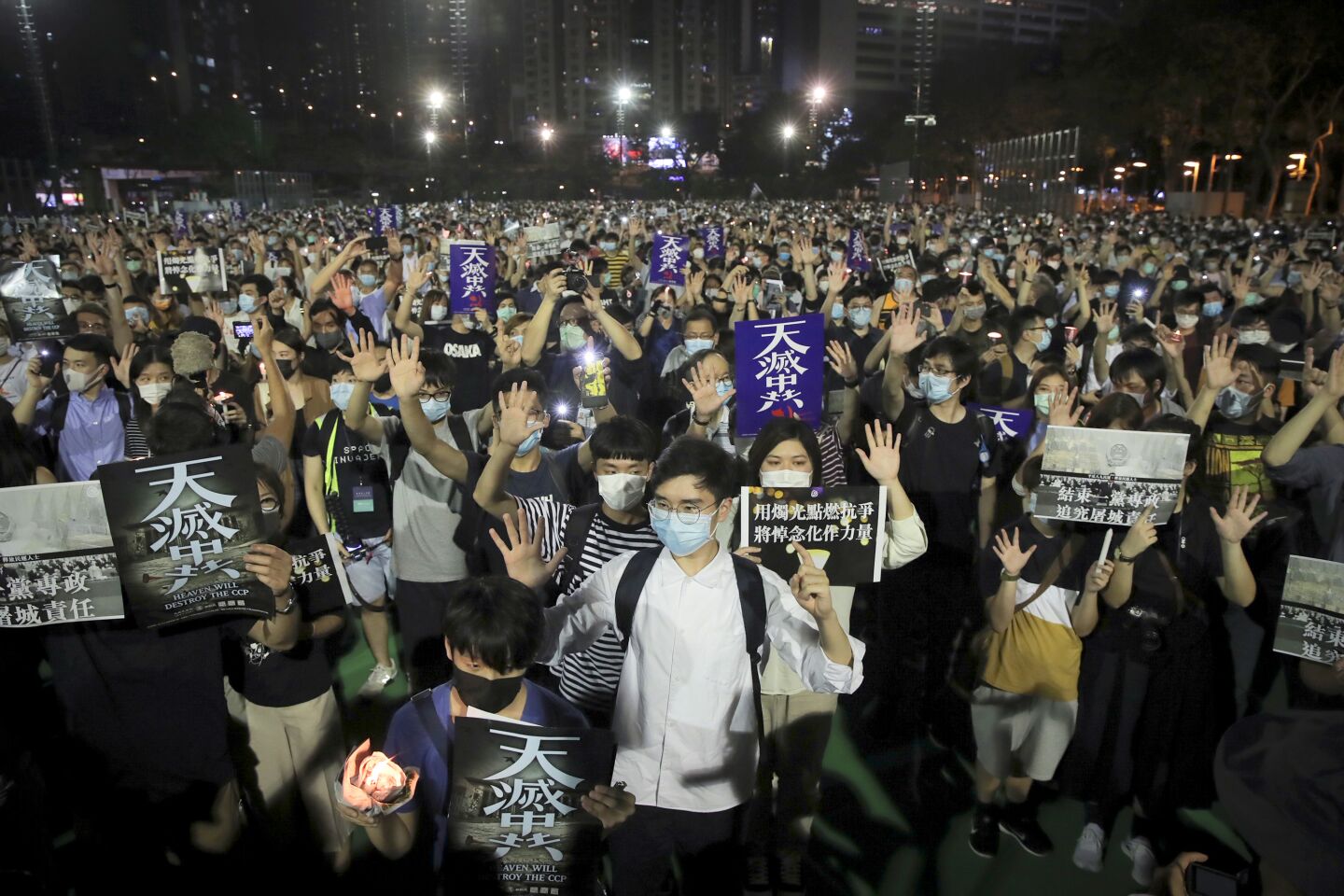 Participants gesture with five fingers, signifying the "Five demands - not one less" and posters read "Heaven will destroy the CCP" during a vigil for the victims of the 1989 Tiananmen Square Massacre at Victoria Park in Causeway Bay, Hong Kong, Thursday, June 4, 2020, despite applications for it being officially denied. China is tightening controls over dissidents while pro-democracy activists in Hong Kong and elsewhere try to mark the 31st anniversary of the crushing of the pro-democracy movement in Beijing's Tiananmen Square. (AP Photo/Kin Cheung)