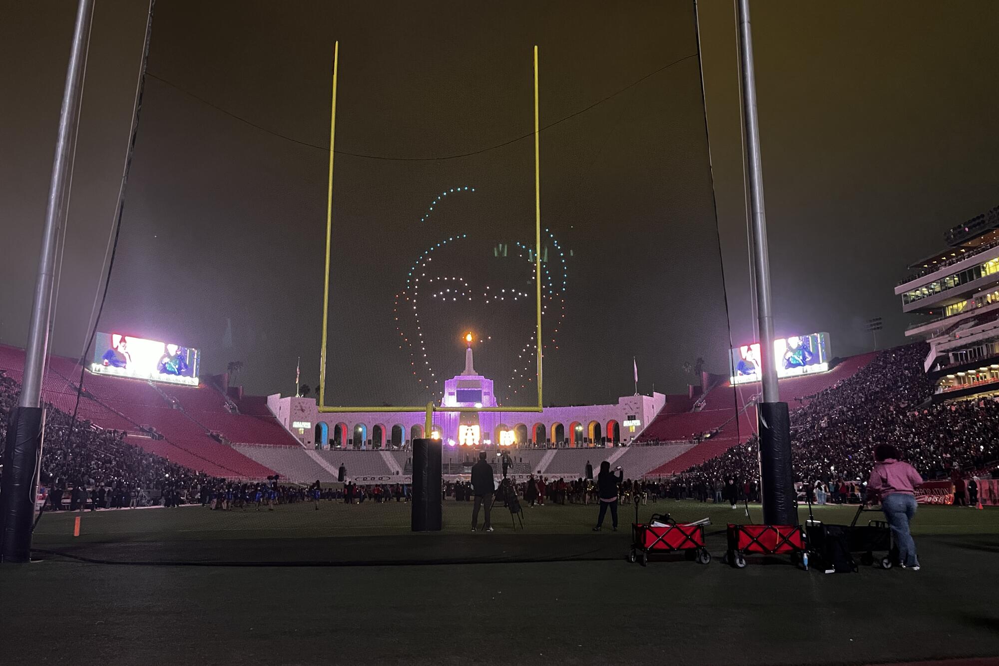 Drones with lights form the shape of a face at a halftime show.