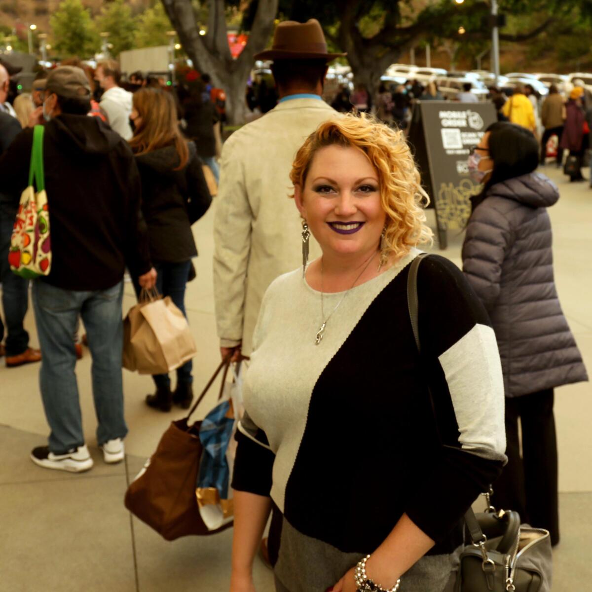 A woman poses for a photo, a line of people behind her.