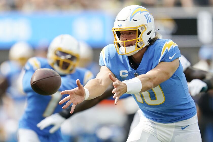 Los Angeles Chargers quarterback Justin Herbert pitches to a running back.