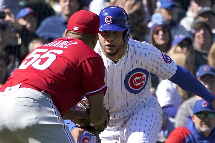 Philadelphia Phillies starting pitcher Ranger Suarez (55) attempts to tag out Chicago Cubs' Willson Contreras on the third base line, but Contreras was called out by home plate umpire Ted Barrett after leaving the base path during the first inning of a baseball game Thursday, Sept. 29, 2022, in Chicago. (AP Photo/Charles Rex Arbogast)