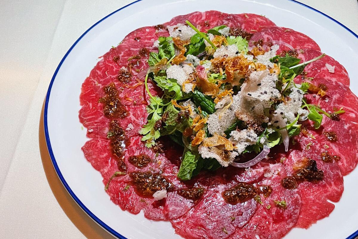 An overhead photo of pho beef carpaccio on a round white plate