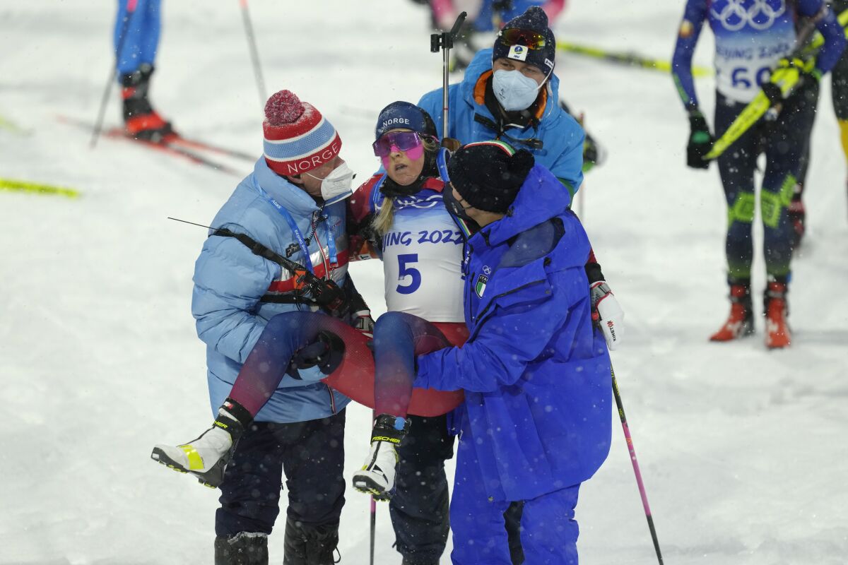 Ingrid Landmark Tandrevold of Norway is helped off the track after the women's 10-kilometer pursuit race at the 2022 Winter Olympics, Sunday, Feb. 13, 2022, in Zhangjiakou, China. (AP Photo/Kirsty Wigglesworth)