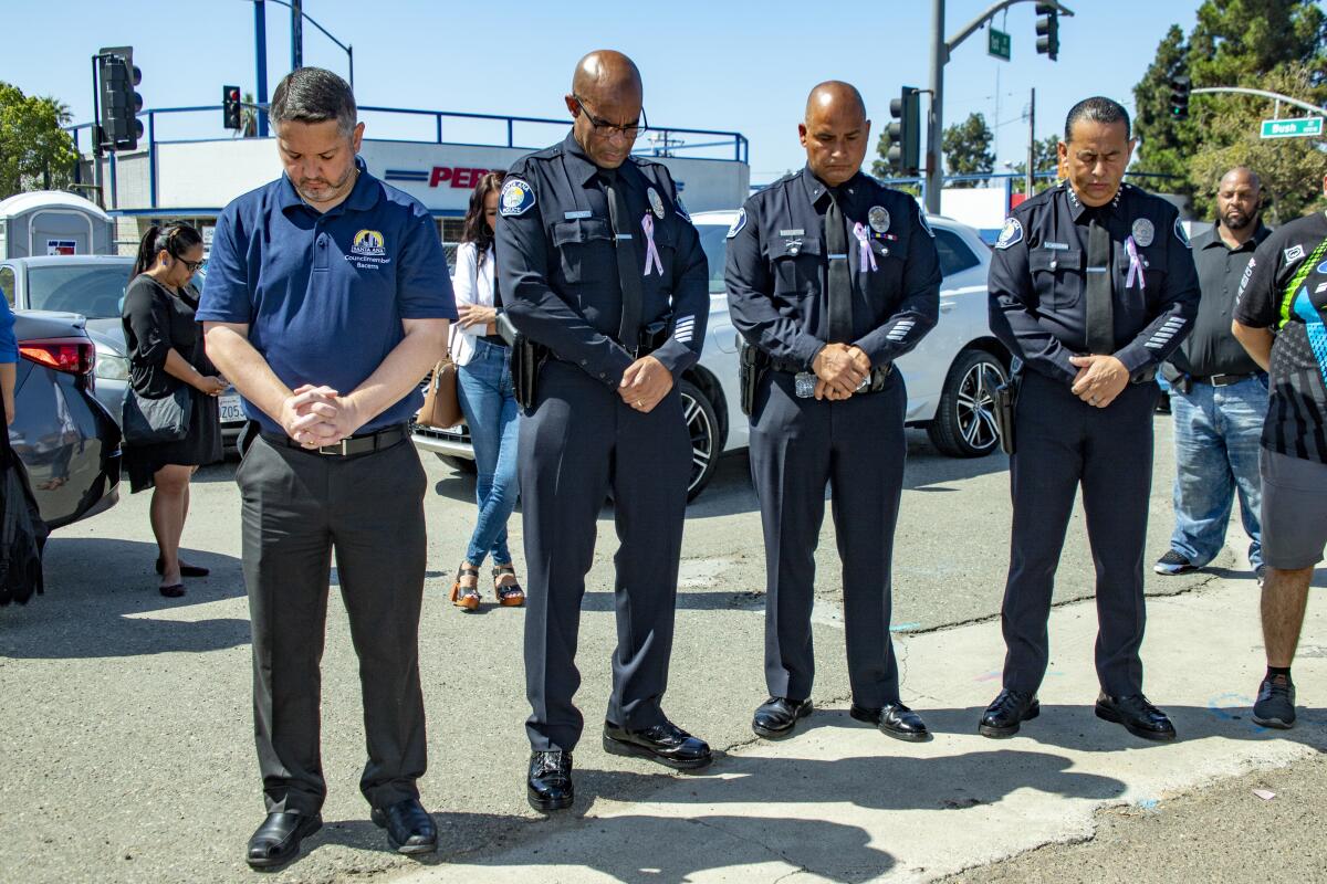 Councilman Phil Bacerra, officers Matthew McLeod and Jose Gonzalez and Police Chief David Valentin bow their heads.