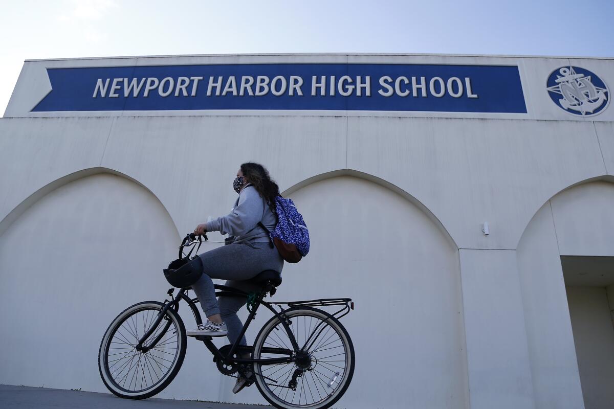 A student rides her bicycle in front of Newport Harbor High School.