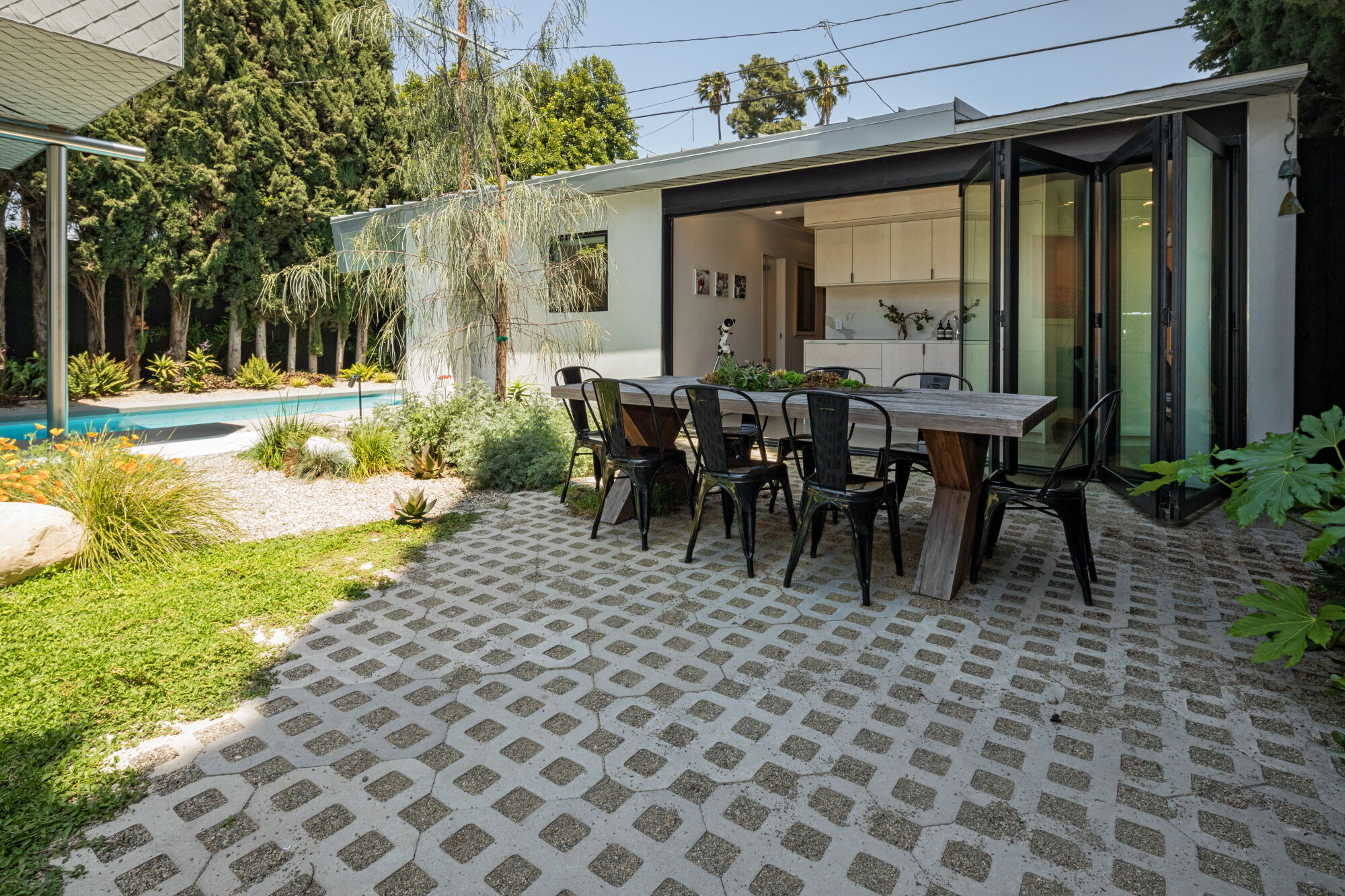 Through folding glass doors, a kitchenette opens to an outdoor dining patio.