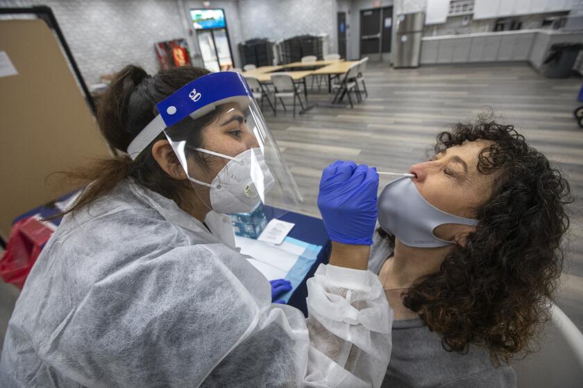 CALABASAS, CA - SEPTEMBER 02, 2020: Laura Duggan, right, office assistant at Lupin Hill Elementary School in Calabasas, is given a nasopharyngeal swab test to detect COVID-19 by phlebotomist Jessica Garcia at Arthur E. Wright Middle School in Calabasas. Las Virgenes School District employees on a voluntary basis were given a nasopharyngeal swab test to detect COVID-19 and also had their blood drawn to have it tested for antibodies to determine if they have had the coronavirus infection within the last 2 months. (Mel Melcon / Los Angeles Times)