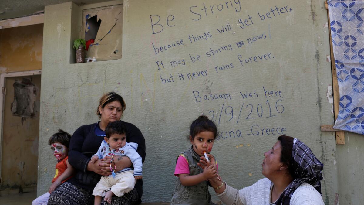 In this photo taken Sept. 13, a Kurd Syrian mother gives cough syrup to her child at Ritsona refugee camp near Athens.