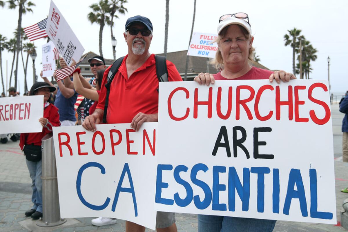 Wally Thomas of Lake Forest and Denean MacAndrew of Mission Viejo take part in a protest in Huntington Beach on May 9.