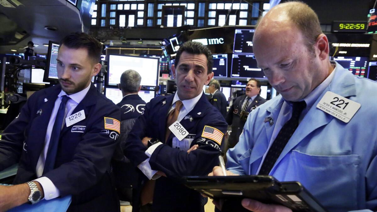 Specialists Matthew Greiner, left, and Peter Mazza, center, work with trader Peter Mancuso on the floor of the New York Stock Exchange.
