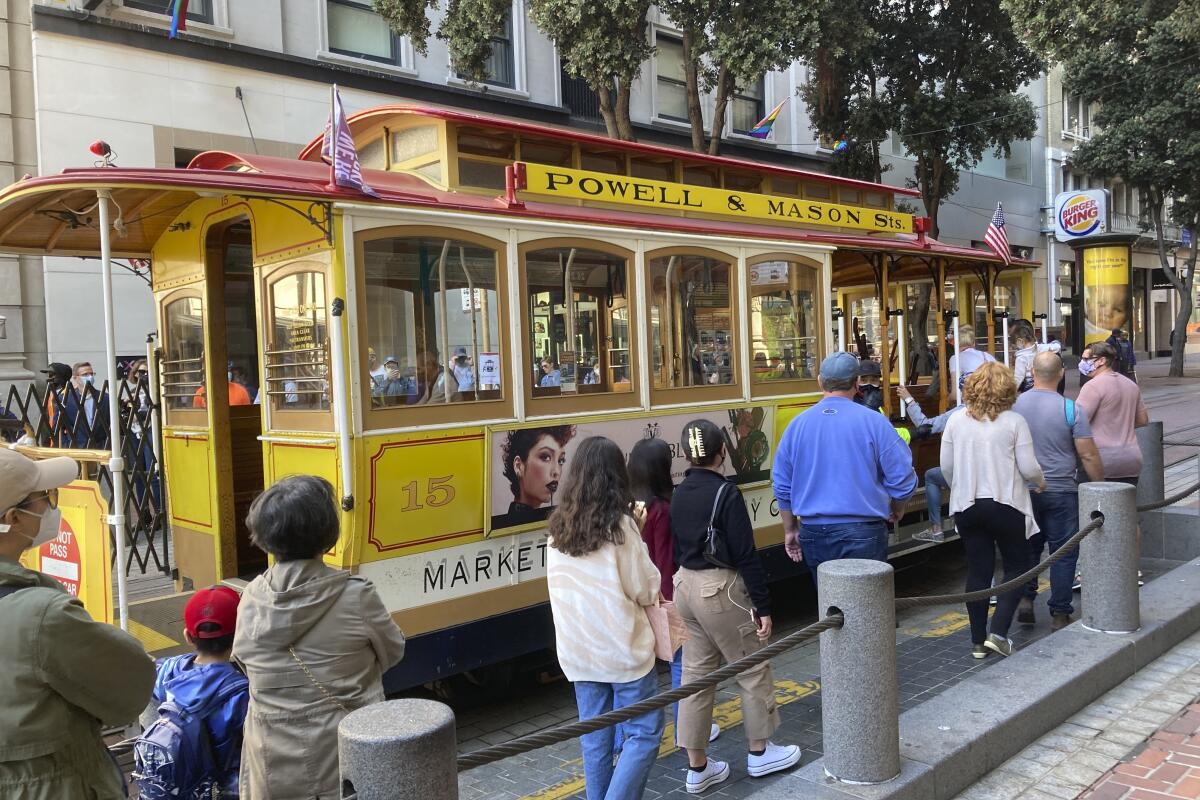 People line up to board a cable car at the Powell Street turnaround plaza in San Francisco on Monday.