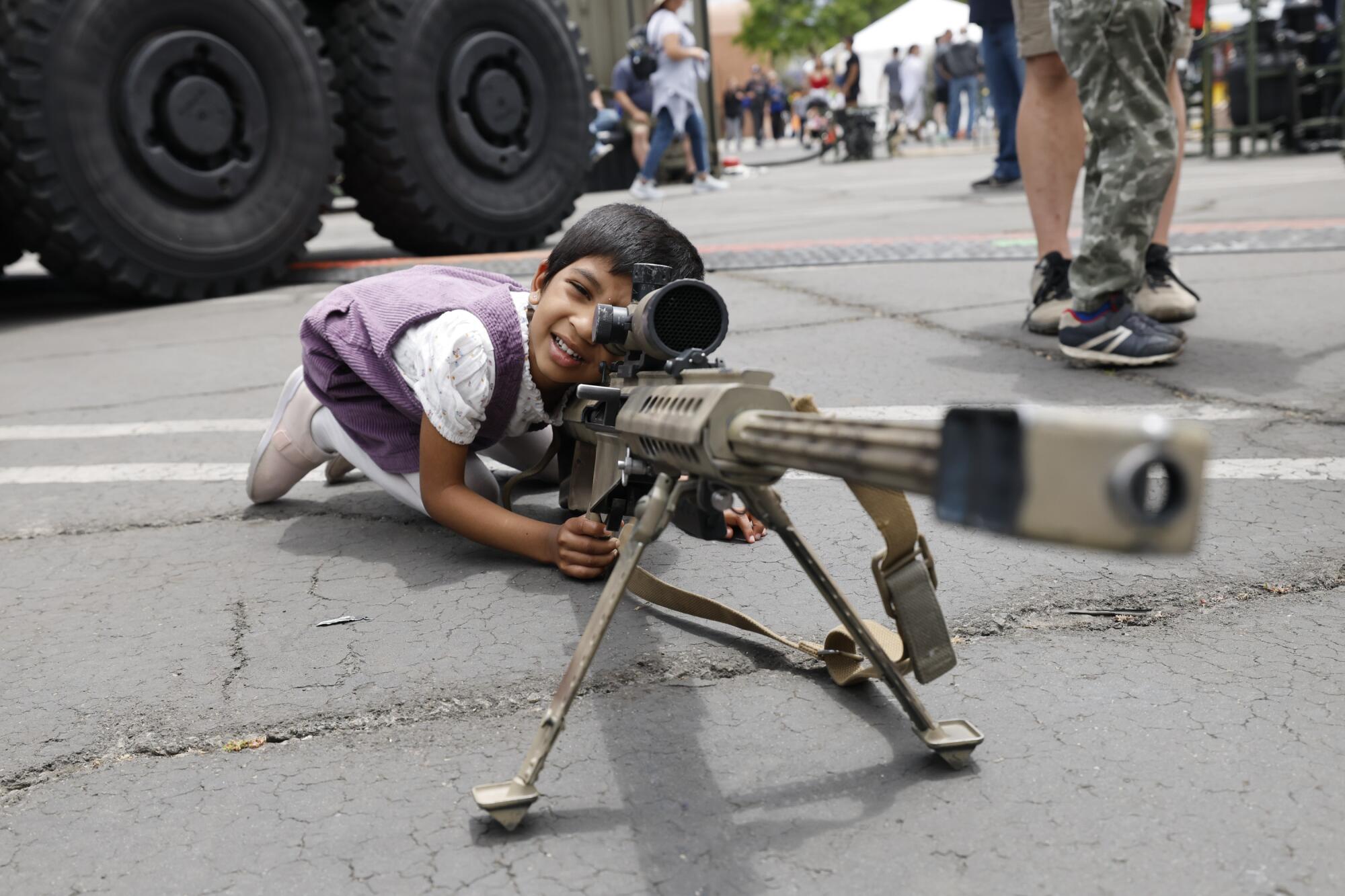 A child looks down the scope of a large gun.