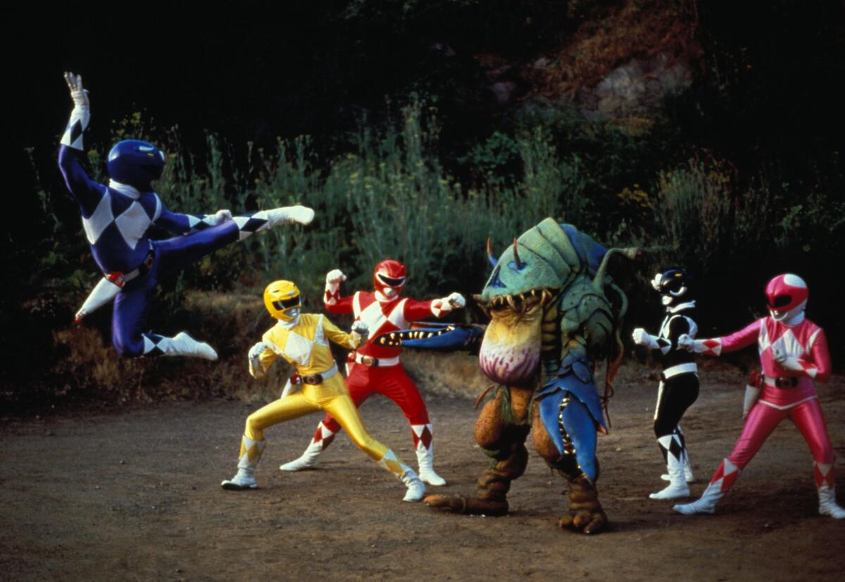 A group of Power Rangers fight a monster in a field.