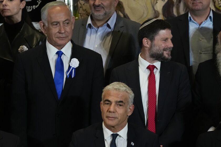Israeli Prime Minister Yair Lapid, center, Likud Party leader Benjamin Netanyahu, left, far-right Israeli lawmaker Bezalel Smotrich and leaders of all Israel's political parties pose for a group photo after the swearing-in ceremony for Israeli lawmakers at the Knesset, Israel's parliament, in Jerusalem, Tuesday, Nov. 15, 2022. Israeli lawmakers were sworn in at the Knesset, on Tuesday, following national elections earlier this month. (AP Photo/Tsafrir Abayov)