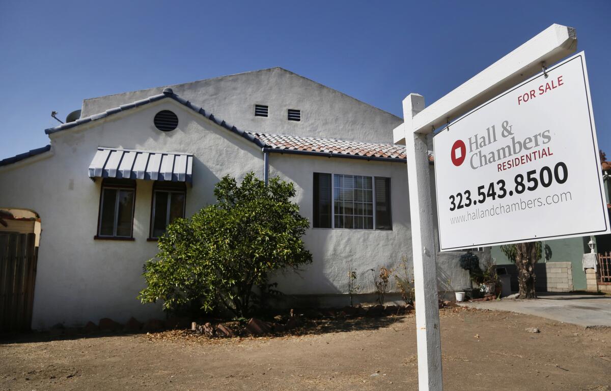 A realty sign hangs in front of a home for sale in Los Angeles. Long-term mortgage rates edged higher this week.