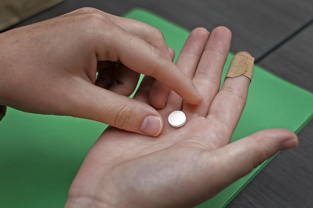 A patient prepares to take the first of two pills 