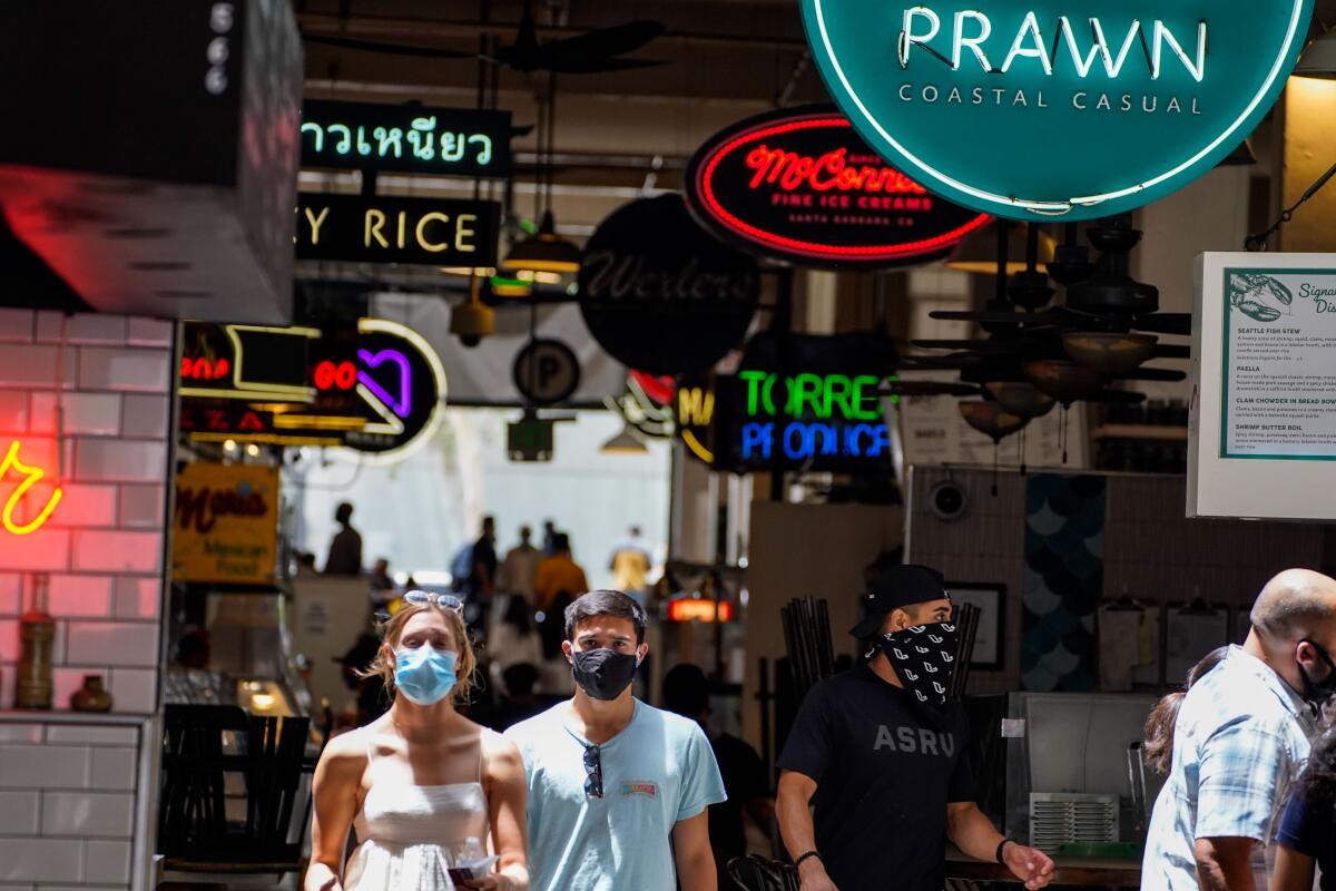 People wearing masks walk in downtown Los Angeles in June 2020.