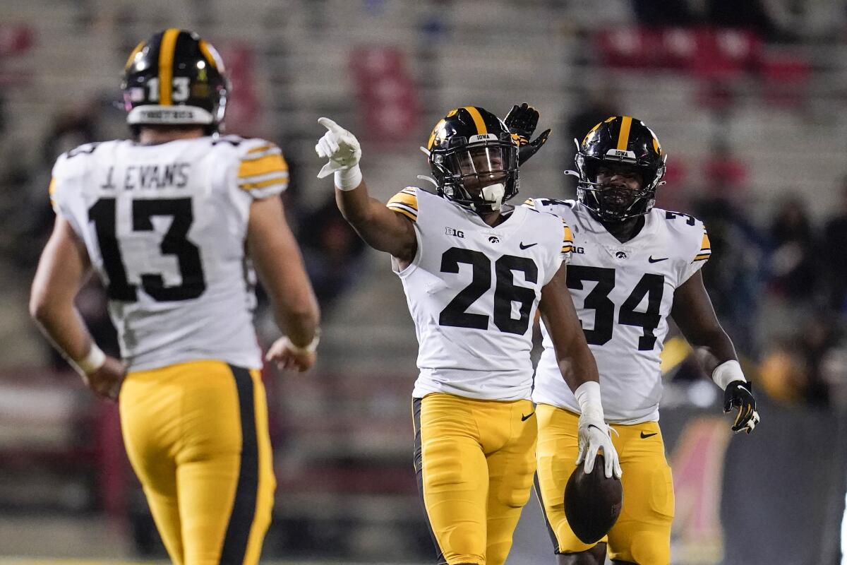 FILE - Iowa defensive back Kaevon Merriweather (26) reacts after making an interception on a pass from Maryland quarterback Taulia Tagovailoa, not visible, during the second half of an NCAA college football game in College Park, Md., in this Friday, Oct. 1, 2021, file photo. Iowa defensive end Joe Evans (13) and linebacker Jay Higgins (34) look on. The key matchup in fourth-ranked Penn State's showdown with No. 3 Iowa pits the Nittany Lions' passing combo of Sean Clifford and Jahan Dotson against a defense that leads the nation with 12 interceptions. (AP Photo/Julio Cortez, File)