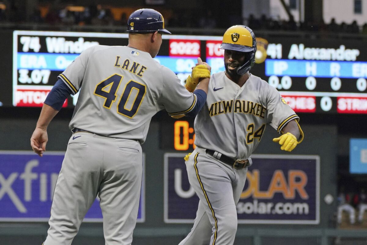 Milwaukee Brewers third base coach Jason Lane congratulates Andrew McCutcheon on his two-run home run off Minnesota Twins pitcher Josh Winder during the first inning of a baseball game Tuesday, July 12, 2022, in Minneapolis. (AP Photo/Jim Mone)