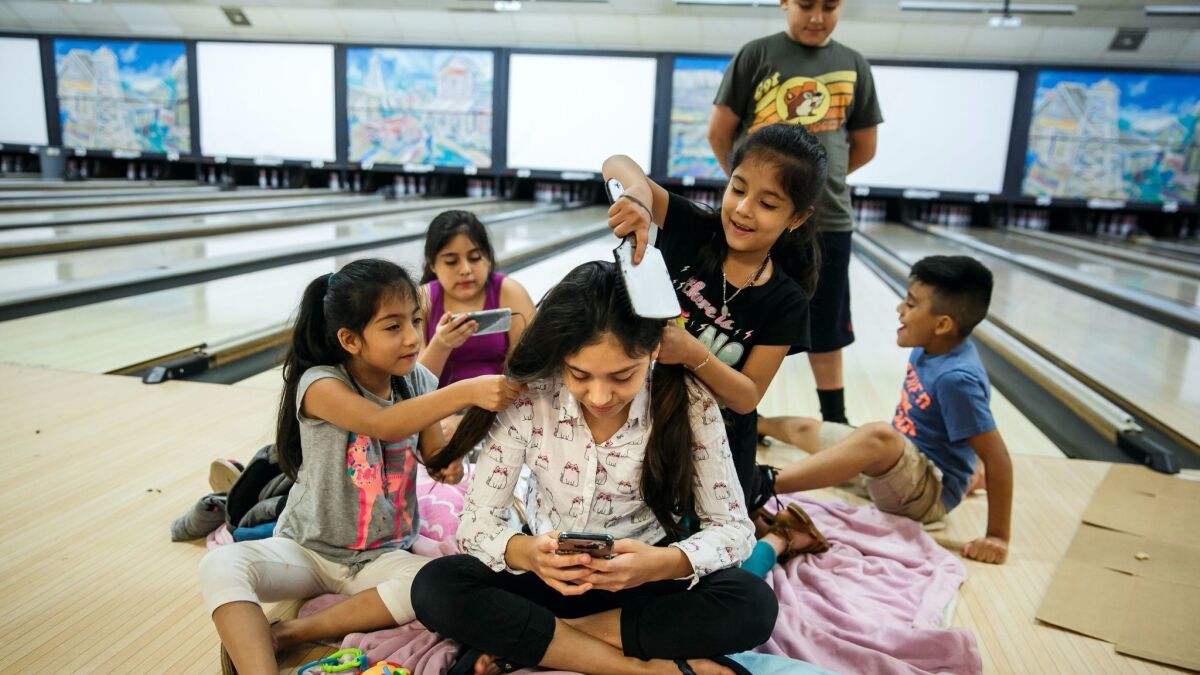 Fatima Flores, 12, center, gets her hair done by Shelly Flores, 7, left, and Ashley Flores, 7, as their family takes shelter at Max Bowl, a bowling alley in Port Arthur, Texas.